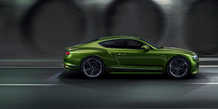  Bentley Praha Bentley Continental GT coupe in Tourmaline Green paint driving in profile on a dark road